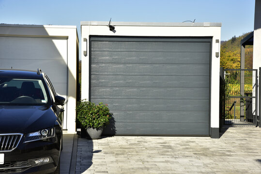 Moderne Beton-Garage mit Automatik-Tor und Edelstahl-Attika in der Hauszufahrt