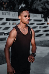 young dark-skinned latino man sitting on the stairs with a good body exercising in the park with...