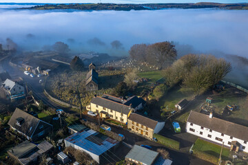 Beautiful morning of drone footage overlooking welsh sceneray small village with fog sheet covering the lower valleys in south wales uk.
