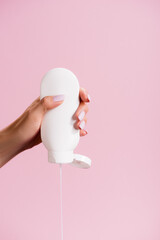 cropped view of woman squeezing lotion isolated on pink, stock image