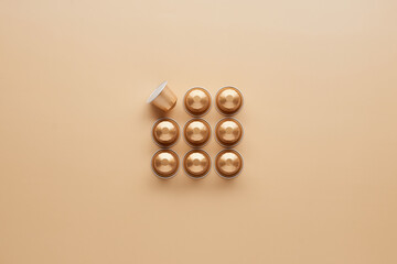 Caffeine, hot drinks and objects concept - close up of golden capsules or pods for coffee mashine...