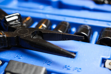 Macro close up of black isolated pliers on blue socket tool set box 