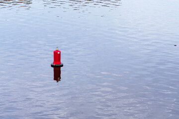 Floating red navigational buoy on blue water of Dnipro River. Buoy in the river. Navigation...