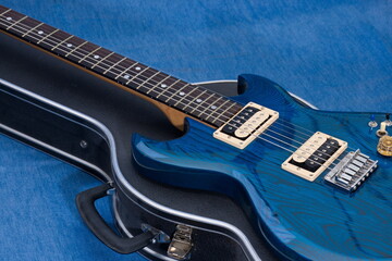 Fototapeta na wymiar Close up of a vibrant blue electric guitar, with the controls reflected in the high-gloss finish on the body of the guitar.
