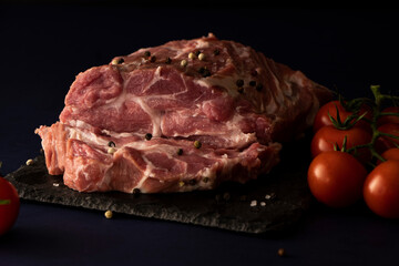 
pork, fresh meat with spices and salt on black. raw steak, tenderloin with tomatoes. semi-finished meat. dish ingredient