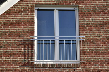 Fototapeta premium Fassade eines modernen neu gebauten Fertighauses mit Vorsatz-Verklinkerung und Edelstahl-Fallschutzgitter an doppelflügeliger Fenstertür