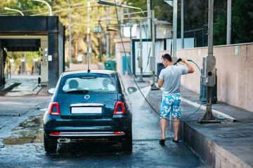 Man cleaning vehicle with high pressure water spray or jet. Summer Car Washing. Cleaning Car Using High Pressure Water