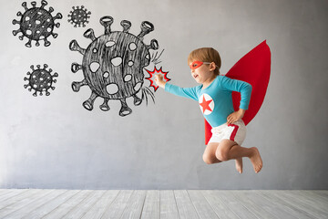 Superhero child jumping against grey concrete background