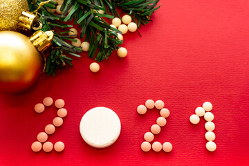 Happy New Year 2021 and Merry Christmas. Numbers 2021 from pills on a red background and scattered vitamins.