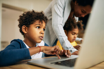 Small black boy e-learning on a computer at home.