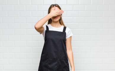 blonde woman covering eyes with one hand feeling scared or anxious, wondering or blindly waiting...