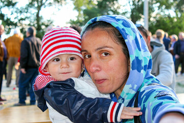 Retrato natural de madre e hijo con gorro balnco y rojo con los labios apretados. Imagen simpçatica