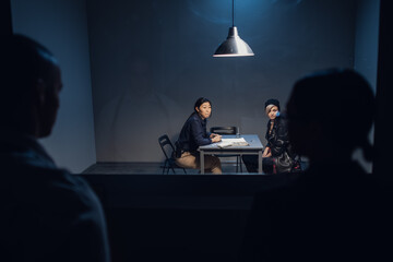 A detective and a witness watch through Gesell mirror as a young criminal drug dealer is interrogated.