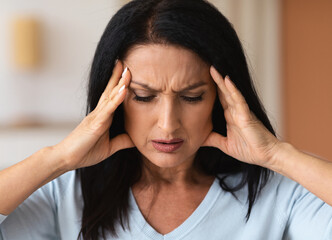 Mature brunette woman touching her temples feeling stress