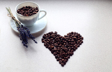 Mug with coffee beans and lavender bouquet, heart of coffee beans on a gray background, side view, space for text