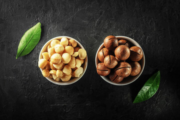 Macadamia nuts in white bowls on a dark concrete background. Top view. 