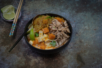 Rice noodles, sweet potato, tofu and king oyster mushroom simmered in vegan Thai red curry, copy space