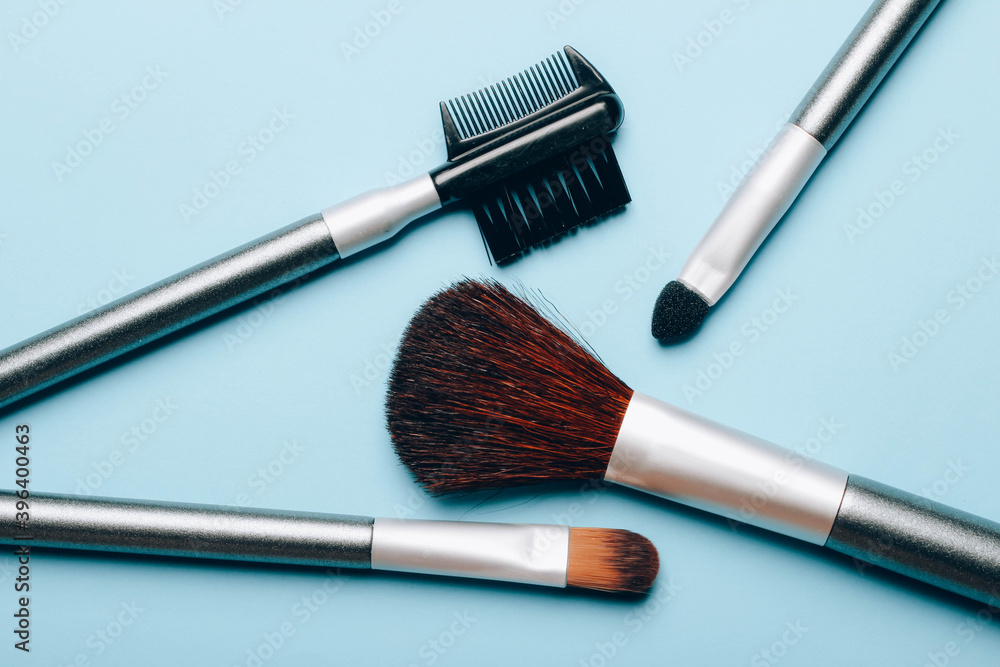 Wall mural set of makeup brushes scattered on blue background. top view point, flat lay.