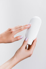 cropped view of woman holding tube of hand lotion isolated on grey, stock image