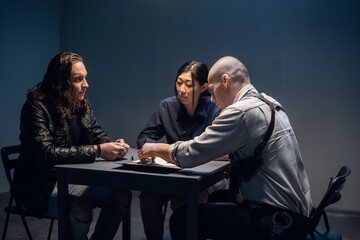 Obraz premium The murder suspect is in the interrogation room with a grim investigator and lawyer