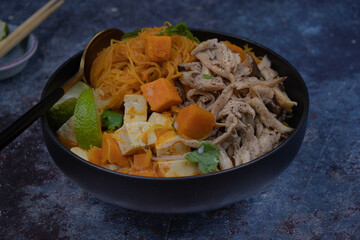 Rice noodles, sweet potato, tofu and king oyster mushroom simmered in vegan Thai red curry, copy space