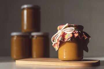 Pumpkin preserves jars on wooden board and white background