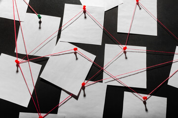 Photo of a black detecftive board with blank paper linked by red thread. - obrazy, fototapety, plakaty