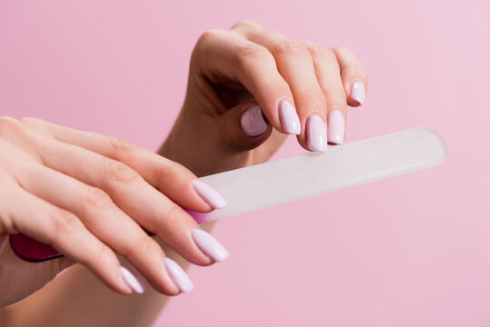 cropped view of woman using nail file isolated on pink, stock image