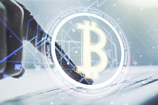 Double exposure of creative Bitcoin symbol with hands typing on laptop on background. Cryptocurrency concept