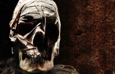 Photo of an old ancient egyptian mummyfied human skull with bondages on dark crypt background.