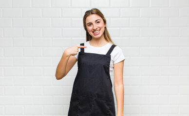 blonde woman looking proud, confident and happy, smiling and pointing to self or making number one...