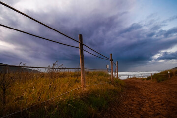 Sandy road between the dunes with storm clouds in the sky