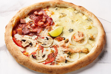 Pizza four seasons with Italian Pepperoni, ham, champignons, salmon, tuna, mussels, squid, Brie cheese, Dorblu cheese, Mozzarella cheese, Parmesan cheese, tomato sauce, lime