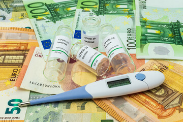 Coronavirus vaccines and digital thermometer on euro banknotes