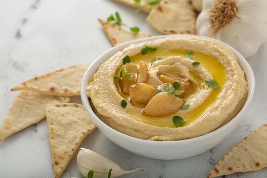 Roasted garlic hummus topped with olive oil and garlic cloves