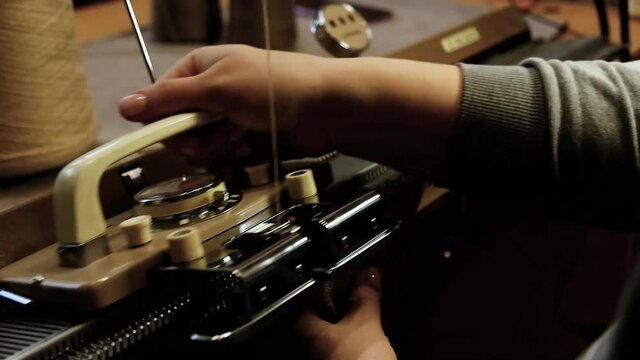 Knitting on a knitting machine, working on a machine. Needlework, hands close-up.