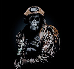 Photo of a fully equipped skeleton zombie soldier standing in armored vest and holding rifle on...