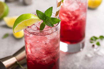 Cranberry lime cocktails in tall glasses served with ice, a slice of lime and fresh mint