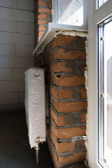 Wall under the window with a heat radiator. Production of apartments, social housing.