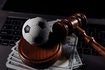 Soccer ball, money and wooden judge gavel close-up. Betting and law concept.