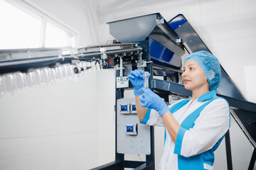 Engineer worker woman checks plastic preform. Production of PET bottles on conveyor belt