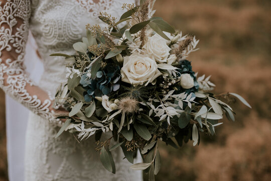 boho bride holding vintage bouquet with white roses and eukalyptus