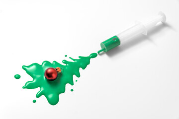 Fototapeta na wymiar Christmas tree shape made with liquid green paint on white background. Syringe with green paint. Creative Coronavirus or 2019-nCoV or COVID-19 vaccine. 