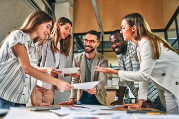 Staff meeting. Group of young modern people in smart casual wear discussing something while working...