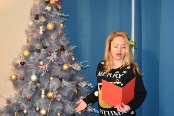 Blond girl holly in her hair sings carol It is a major Christmas tradition together with eating mince pies and drinking mulled wine Everyone is allowed to take part in outdoor and door-to-door singing