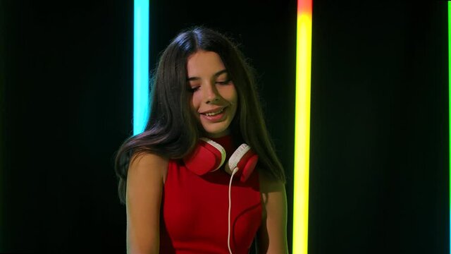Portrait of a young pretty girl in big red headphones dances and enjoys the music. Close up. Slow motion.