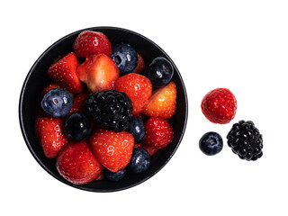 Detailed top view of 3 sorts of fruit in black round bowl, isolated on a white background