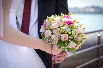 Wedding bouquet in the hands of the bride and groom