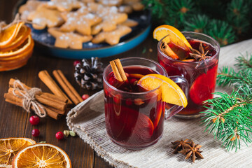 Fragrant, hot punch or mulled wine for Christmas in a glass on a wooden board and branches of a...