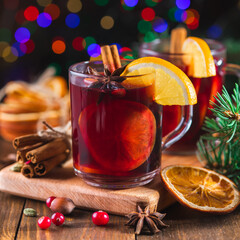 Fragrant, hot punch or mulled wine for Christmas in a glass on a wooden board and branches of a...